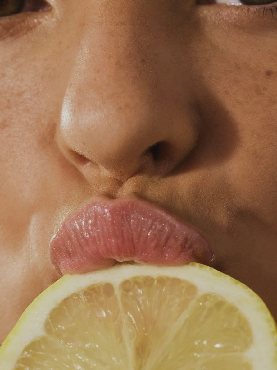 Flat lay of lemons, blueberries, pomegranate, tart cherries, and papaya representing the top healing fruits and their science backed benefits for inflammation and recovery. woman eating close up mouth lips